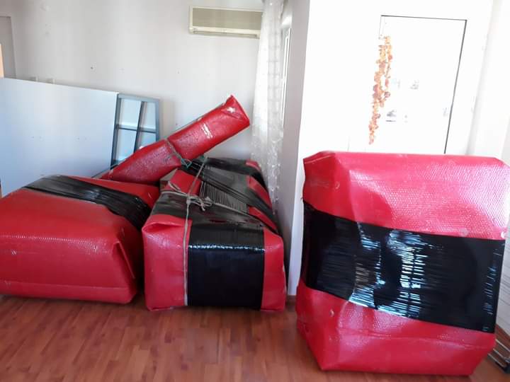 Kırmızı ve siyah bantlarla güvenle paketlenmiş büyük nakliyat eşyaları
